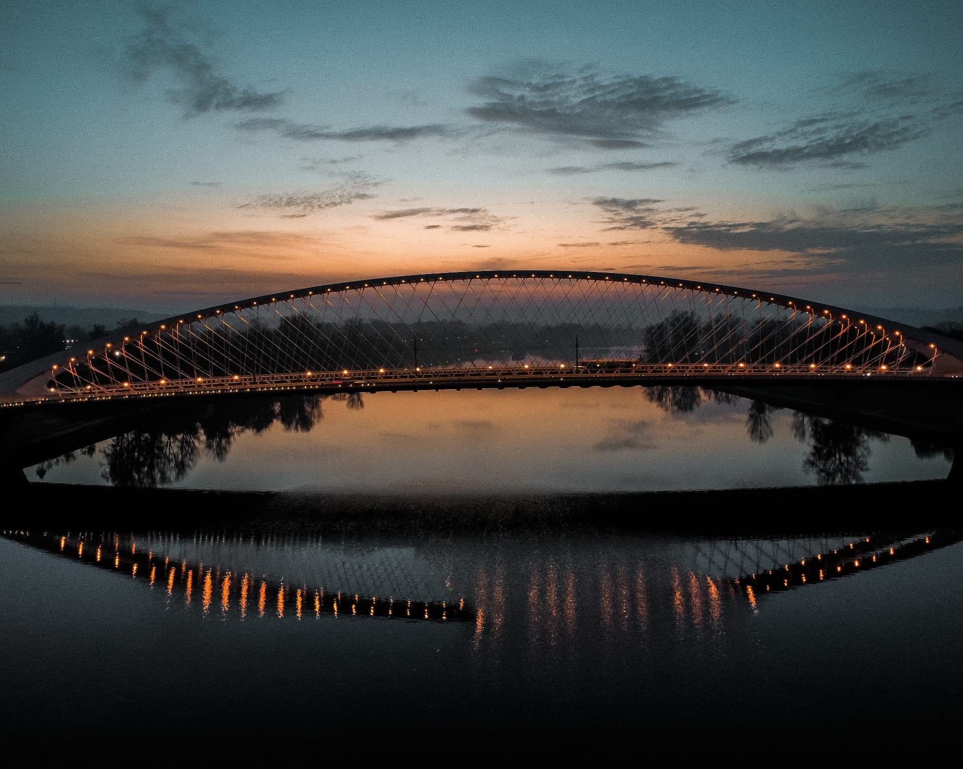 Osvětlený most s odrazem ve vodě při západu slunce